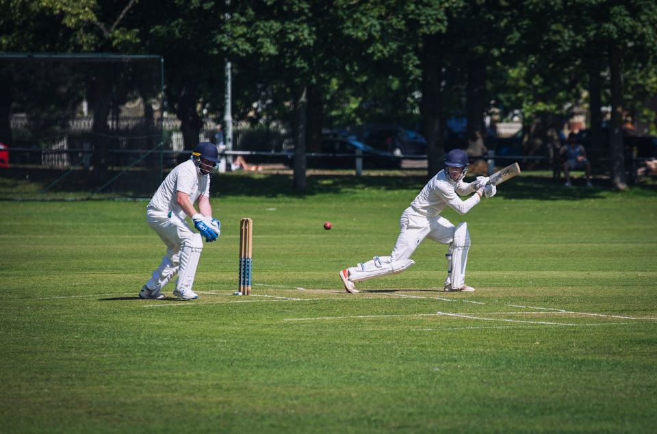 A person in white uniform playing cricket